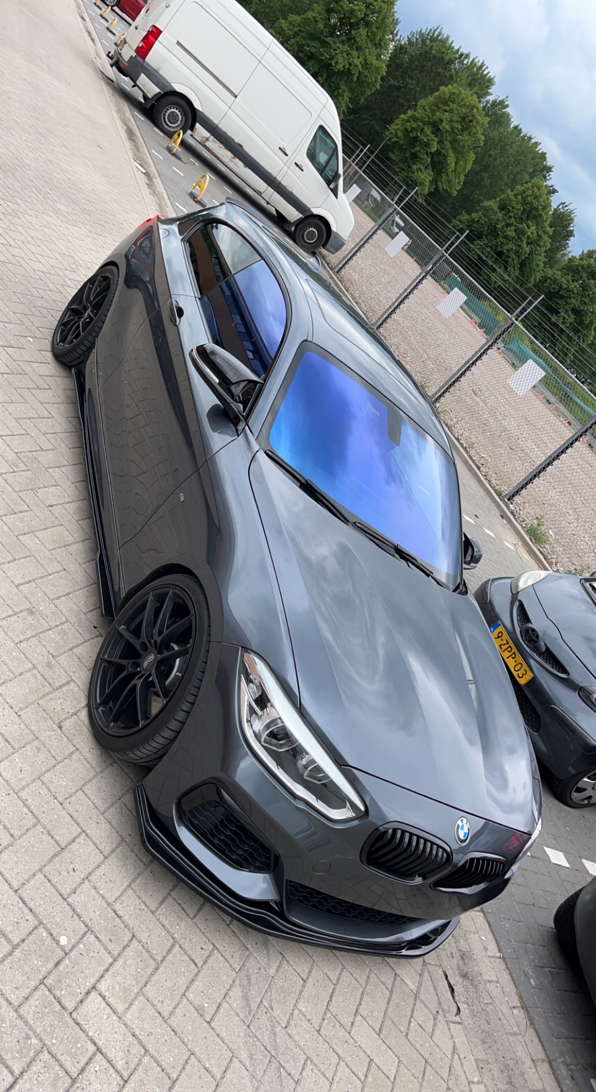 BMW M1 in Tilburg geparkeerd vlakbij een garage op een parkeerplaats. Met de achterruiten zwart getint en chameleon tint